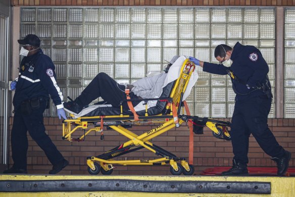 Paramedics wheel a patient wearing a breathing apparatus into the emergency room at Wyckoff Heights Medical Centre in New York on Monday. 