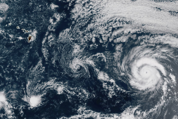 Hurricane Douglas, right, churning in the Pacific Ocean heading towards Hawaii, left. The storm is currently a Category 3 hurricane but is expected to weaken before it arrives in the state on Sunday. 