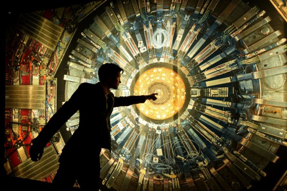 Professor Alan Duffy with a photo of the  LHC’s main magnet during a talk at a CERN exhibition in Sydney. The real magnet is 15 metres tall.