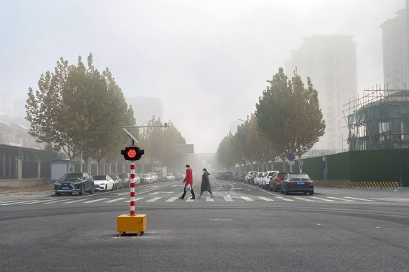 Pedestrians cross a near deserted road in Beijing, China, on Friday.