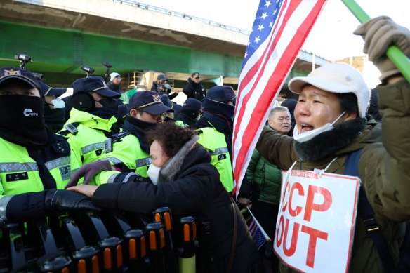 Police officers stand guard as supporters of South Korean President Yoon Suk Yeol protest near the presidential residence in Seoul.