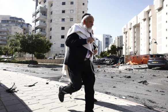 A man runs past cars damaged during a rocket attack in Ashqelon, Israel.
