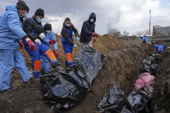 Bodies are placed into a mass grave on the outskirts of beseiged Mariupol in southern Ukraine. 