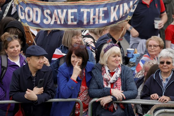 People gather as they wait to watch King Charles III’s procession to his coronation ceremony. 