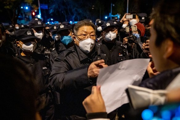 A local official speaks with a demonstrator holding a blank sign during a protest in Beijing.