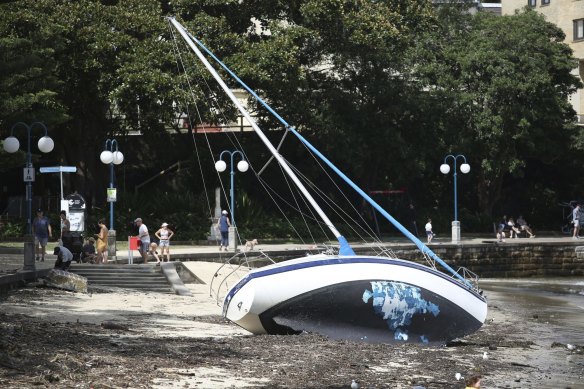 A damaged boat on the shore of Manly’s East Esplanade on Sydney Harbour following massive swells and stormy weather.