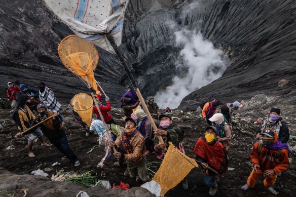 Villagers use nets to catch offerings thrown by Tenggerese worshippers during the Yadnya Kasada Festival at crater of Mount Bromo amid the coronavirus pandemic.