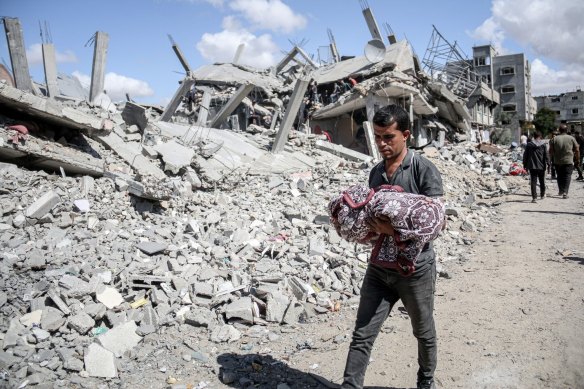 A Palestinian carries away the wrapped body of an infant following an Israeli strike in the east of the refugee camp in al-Bureij, central Gaza, in September.