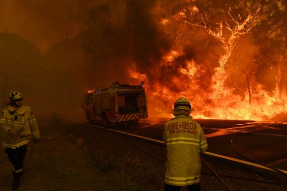 Fire and Rescue NSW firefighters escape flames from the Gospers Mountain fire north-west of Sydney in mid-December 2019.