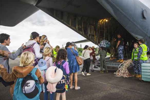 Australian and other tourists board an Australian Airforce Hercules as they prepare to depart from Magenta Airport in Noumea, New Caledonia on Tuesday.
