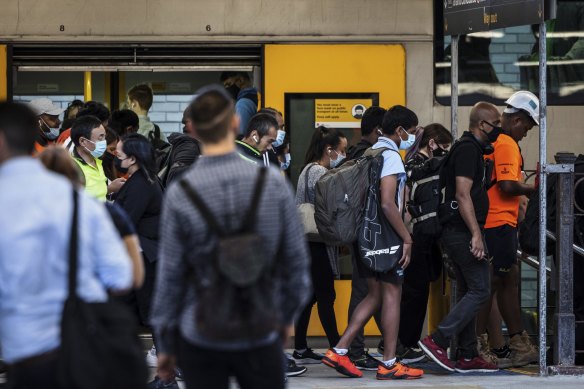 Commuters board a train at Central Station after services resumed at reduced capacity on Tuesday.