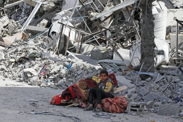 A Palestinian boy sits with recovered possessions near destroyed buildings following the withdrawal of the Israeli military from Hamad City, west of Khan Younis, Gaza, on Wednesday.