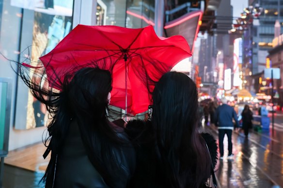 Pedestrians sharing an umbrella near Times Square in New York.