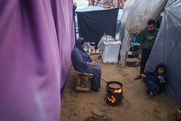 Displaced Palestinians cook food in a temporary shelter in a camp in Gaza.