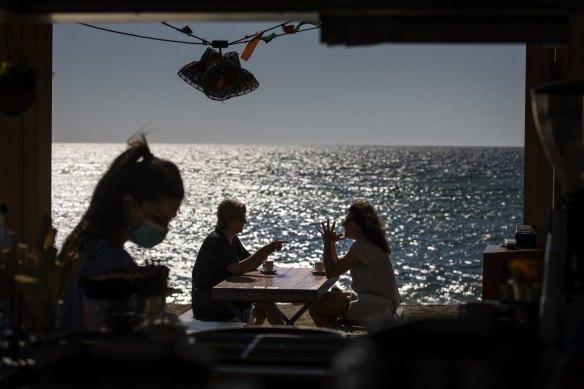 People sit on a terrace at a beach in Barcelona, Spain. Eased lockdown measures in some areas allow social gatherings in limited numbers, restaurant and bar service with outdoor sitting.