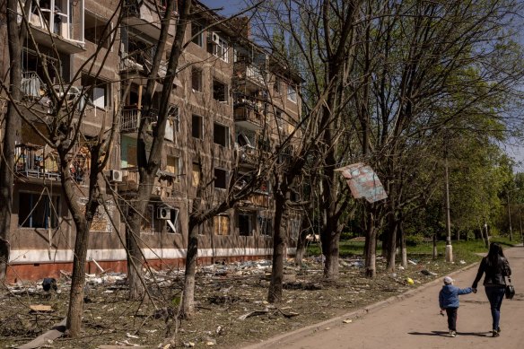 A woman and her child walk past an apartment block in Kramatorsk damaged by a Russian missile strike. 