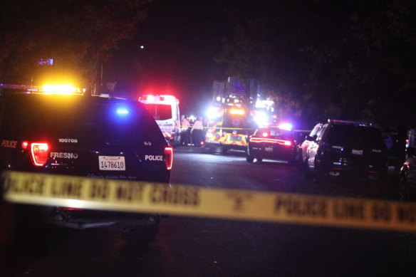 Police and emergency vehicles work at the scene of a shooting at a backyard party.