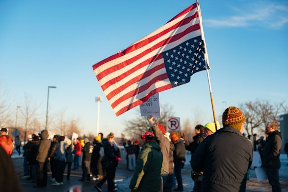 I manifestanti a St. Paul, Minnesota, portano una bandiera americana capovolta per protestare contro l'uccisione di un agente dell'ICE. 