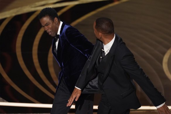 Will Smith, right, hits presenter Chris Rock on stage while presenting the award for best documentary feature at the Oscars.