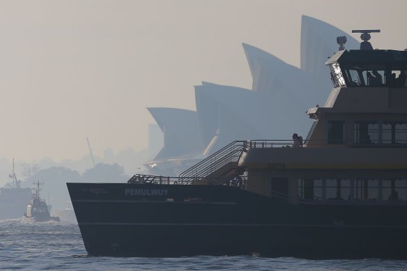 A ferry sails past the Sydney Opera House as winds blow smoke from bushfires over the CBD in Sydney.
