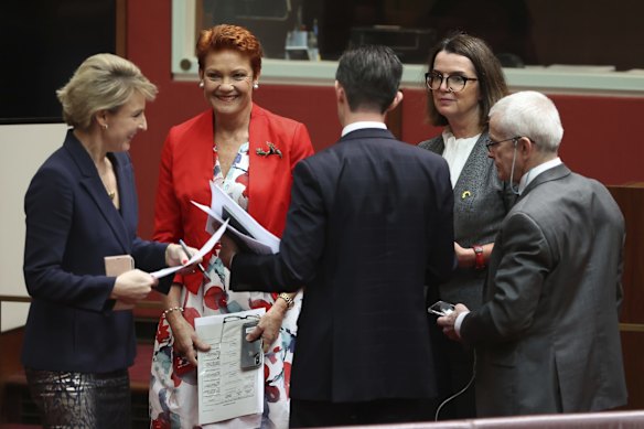 Liberal ministers Michaelia Cash, Simon Birmingham and Anne Ruston speak to One Nation’s Pauline Hanson and Malcolm Roberts during debate in the Senate on March 18, 2021.