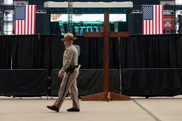 Um soldado do estado do Arizona passa por uma grande cruz antes do serviço memorial.