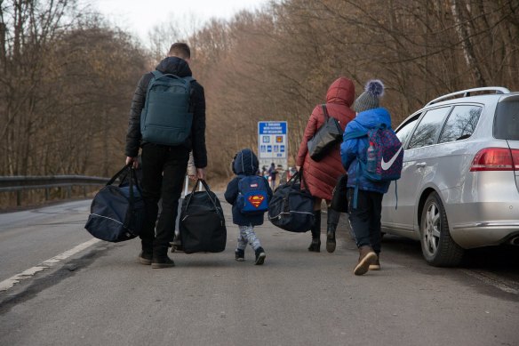 A family carry their bags and walk on the street after they crossed the Slovak - Ukrainian International crossing border on February 24, 2022 in Ubla, Slovakia.