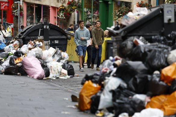 People walk past large piles of rubbish in Edinburgh, Scotland, on Aug. 29.  Rubbish collection has been suspended in the Scottish capital while waste workers are on strike.