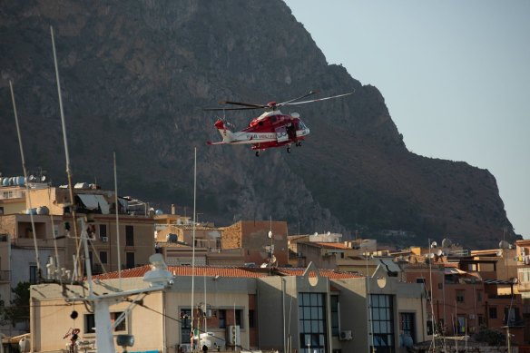 A rescue services helicopter flies over rooftops during search operations for the luxury yacht Bayesian, in Porticello, Italy. 
