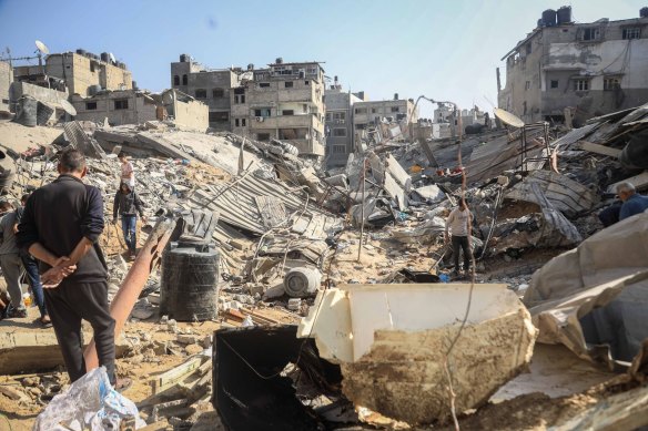 Palestinians walk among what is left of residential buildings.