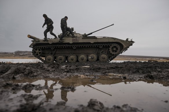 Ukrainian servicemen walk on an armored fighting vehicle during an exercise in a Joint Forces Operation controlled area in the Donetsk region, eastern Ukraine, Thursday, Feb. 10, 2022.