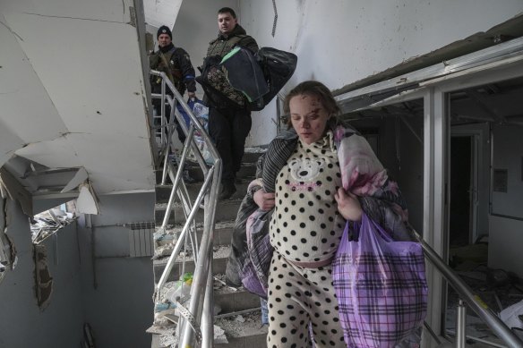 An injured pregnant woman walks downstairs in a maternity hospital damaged by shelling in Mariupol, Ukraine.