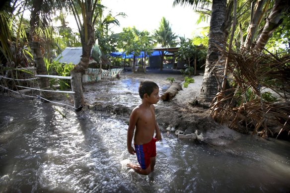 A child wades through sludge on the Island Republic of Kiribati, which often experiences inundation on high tides and is one of a number of low-lying nations exposed to the worst effects of rising waters due to climate change.