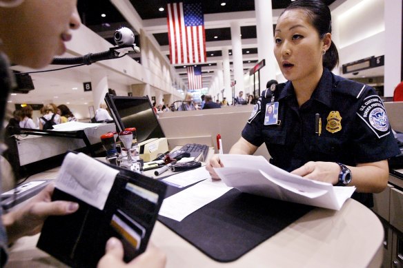 A US Customs and Border Protection officer checks the passport and paperwork of a visitor at Los Angeles International Airport.