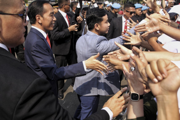 Indonesia’s President Jokowi (left) and his son Gibran Rakabuming Raka greet supporters in 2019.