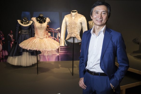 Brisbane’s 2023 Business Person of the Year, dancer Li Cunxin AO posing with works from the exhibition Mao’s Last Dancer the Exhibition