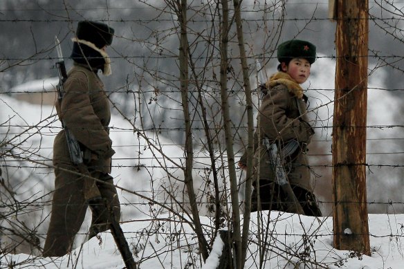 A North Korean soldier looks back as she and another patrol on a pathway along the bank of the Yalu River on the China-North Korea border.