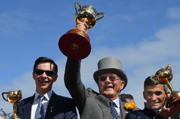 Lloyd Williams lifts his sixth Melbourne Cup after Rekindling's triumph in 2017, flanked by trainer Joseph O'Brien and jockey Corey Brown