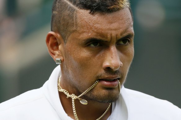Tennis player Nick Kyrgios holds his necklace in his mouth during a match