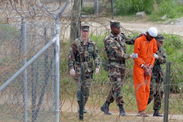 An unidentified detainee is led by military police to be interrogated at Camp X-Ray at the US Naval Base at Guantanamo Bay, Cuba, in 2002. At the time the image was taken the facility held 158 al-Qaeda and Taliban prisoners.