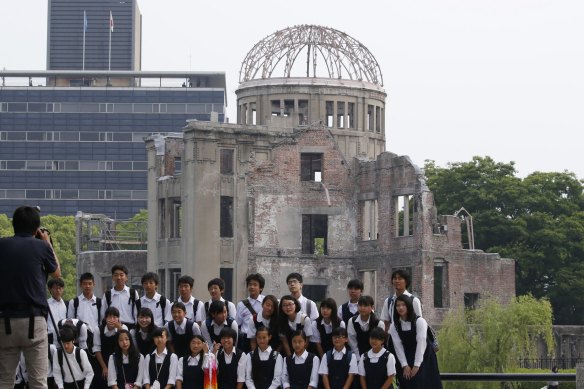 School children pose for a group photo with the Atomic Bomb Dome as a backdrop in the Hiroshima Peace Memorial Park.