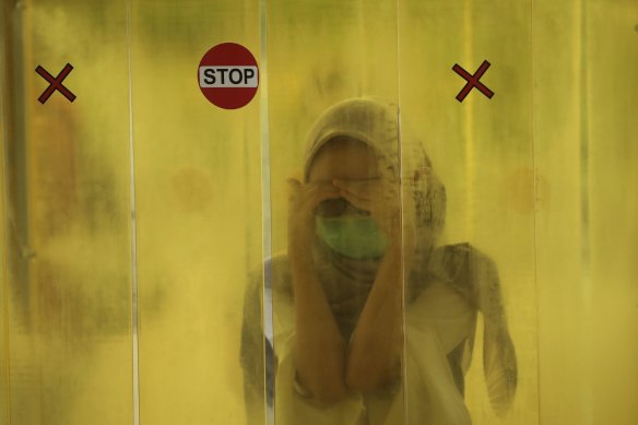 A woman is sprayed with disinfectant in a special booth before entering a shopping mall in Jakarta.
