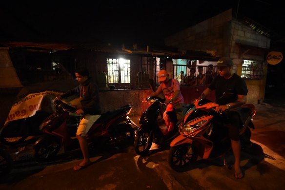 Police on motorbikes leave the scene where three men were slain in a drug related killing in Caloocan, Manila, Philippines, in September. 