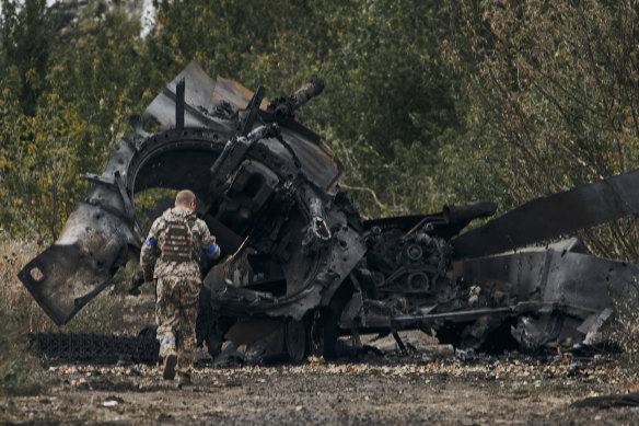A Ukrainian soldier inspects a Russian tank destroyed in a battle in a freed territory on the road to Balakleya in the Kharkiv region.