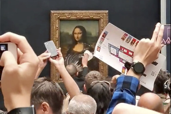 A security guard cleans the smeared cream from the glass protecting the Mona Lisa.