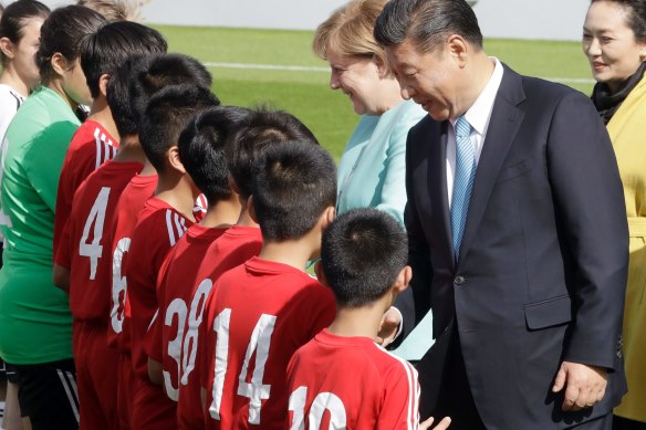 Then-German chancellor Angela Merkel and Chinese President Xi Jinping greet players before a match between the under-12 teams of Germany and China in Berlin in 2017.