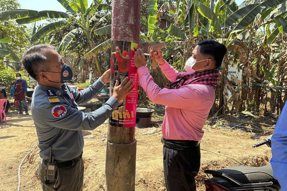 A Cambodia police officer and animal health officer place posters warning of H5N1 virus threats, in Prey Veng eastern province Cambodia, on Thursday.