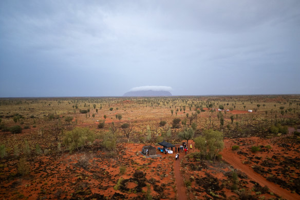 Uluru in the distance covered by cloud as guests gather for Field of Light.