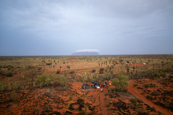 Uluru in the distance covered by cloud as guests gather for Field of Light.