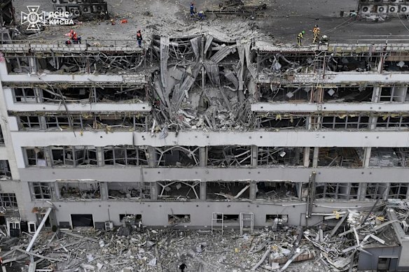 Emergency services personnel clear up rubble from a damaged office building following a Russian missile attack in Kyiv.